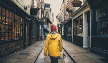 A rear view of a female in a bright yellow coat walking along the historic street known as The Shambles in York, UK which is a popular tourist destination in this Yorkshire city.