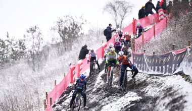 Cyclocross riders navigate an off-camber section on a snowy course