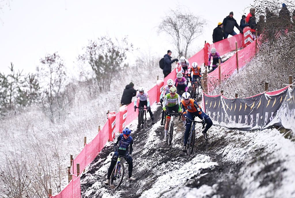 Cyclocross riders navigate an off-camber section on a snowy course