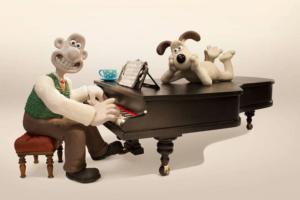 wallace and gromit sitting at and laying on top of a piano