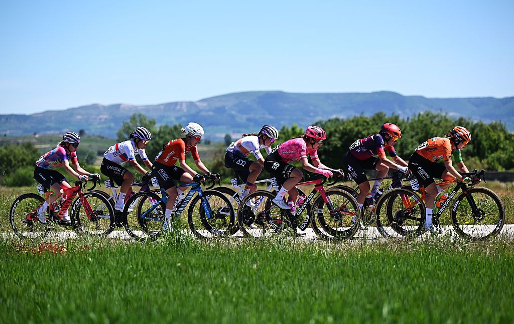 Side shot of a group of riders riding a stage of the Vuelta a Burgos 2025, with rolling Spanish hills in the background