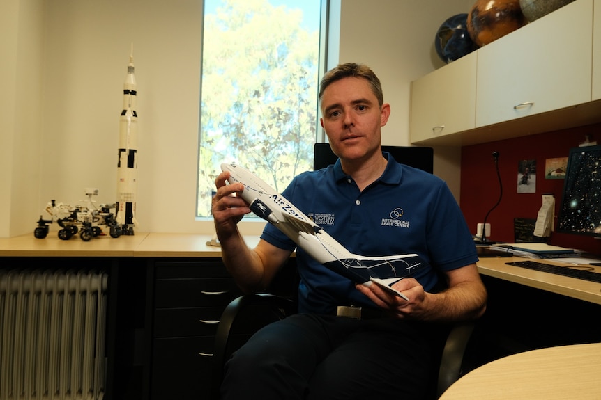 Astrophysicist Danail Obreschkow holds a model rocket in his office at UWA.