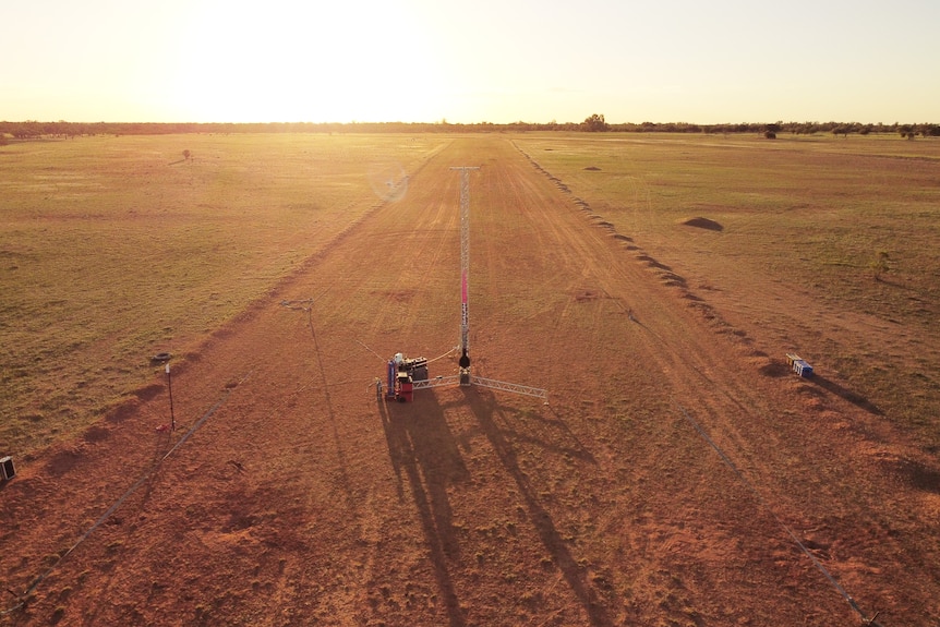 A metal rail for a rocket to be affixed to, on a dirt patch in an outback setting