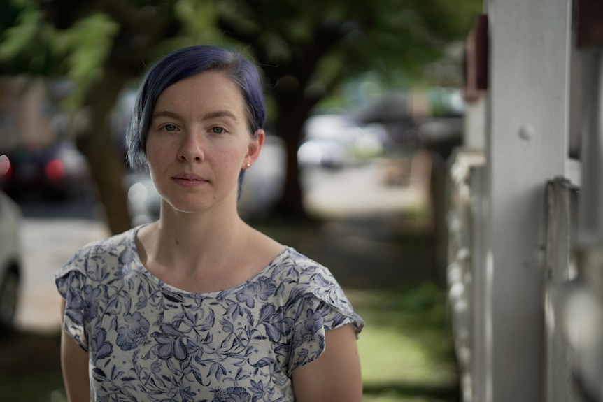 A woman with light blue hair standing outside.