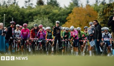 A line up of cyclists in bright lycra at a starting line-up