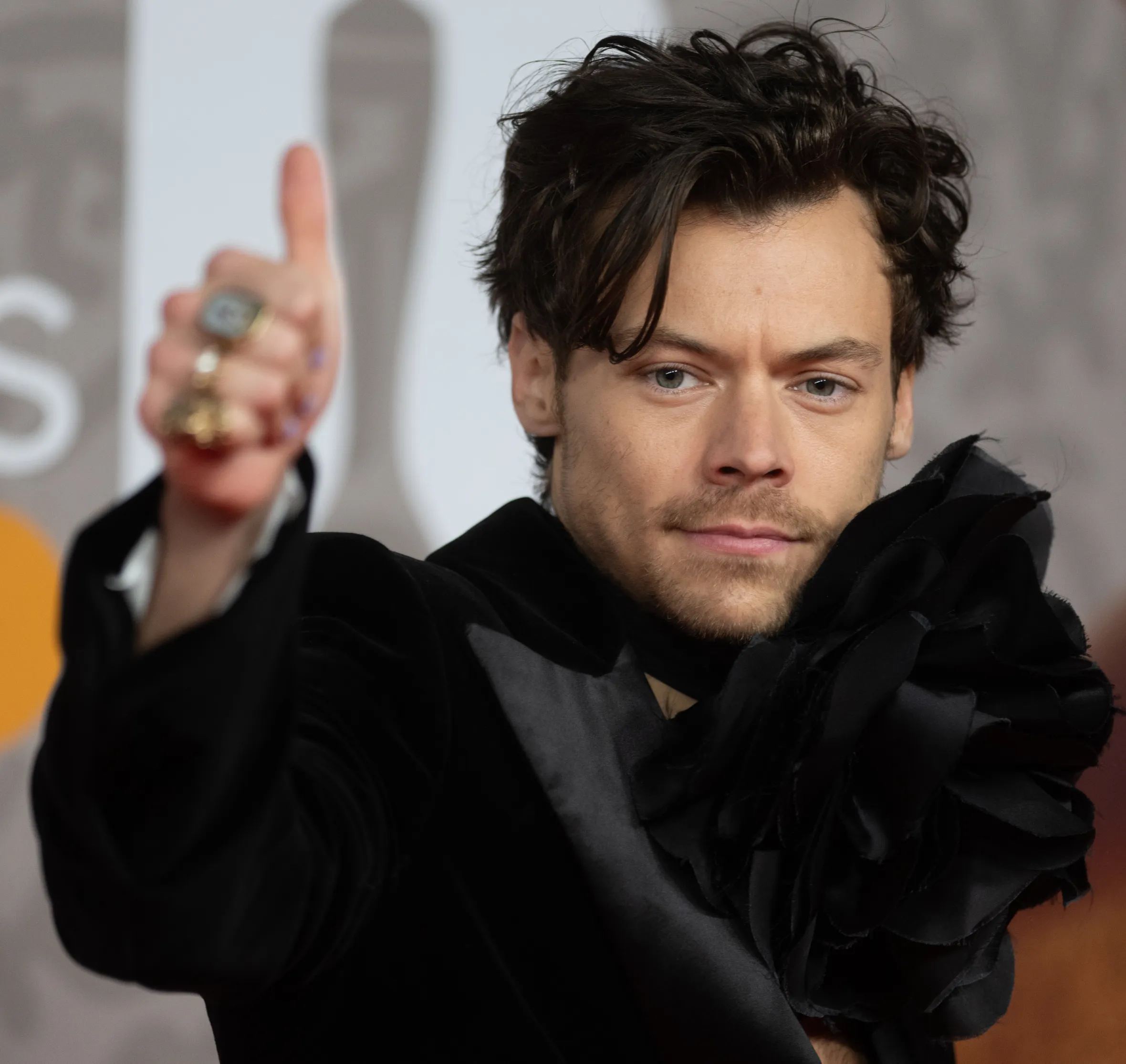 Harry Styles at the BRIT Awards 2023 giving a thumbs up.