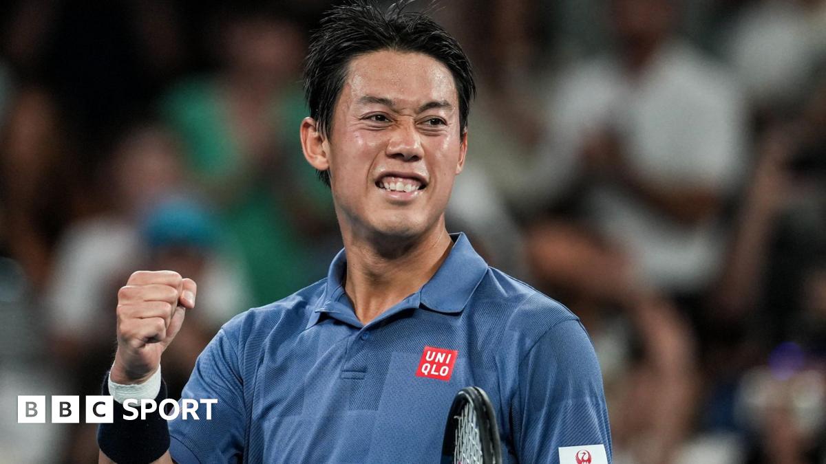 Japan player Kei Nishikori, in a blue polo shirt, pumps his fist on a tennis court, blurred crowd behind him