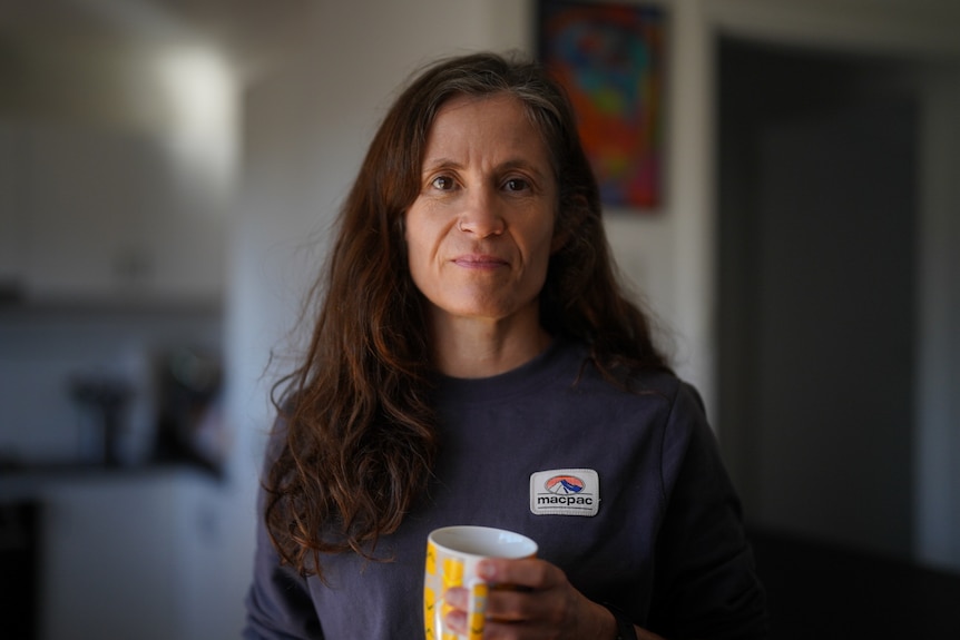 A woman holds a coffee mug.