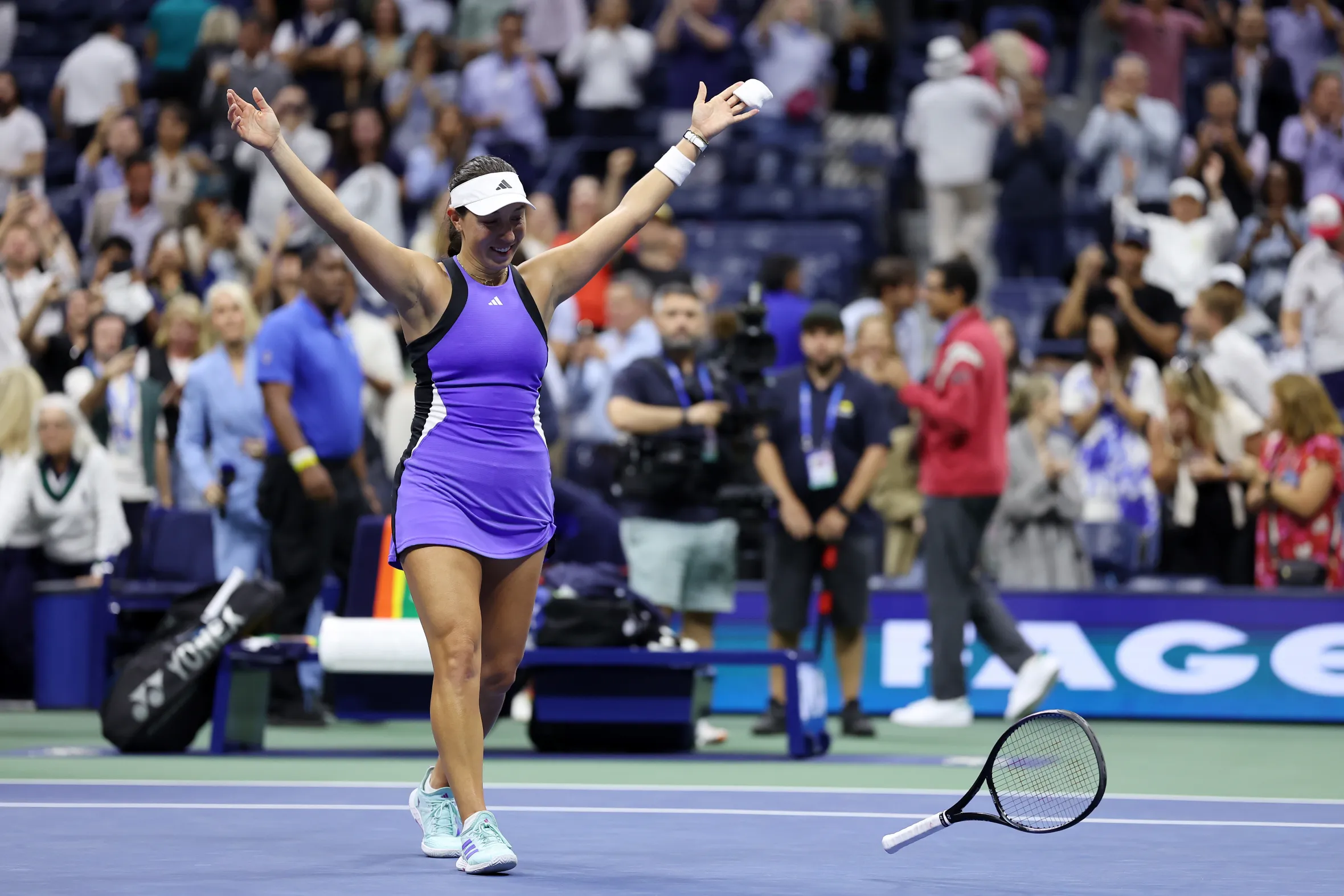 Jessica Pegula celebrates her victory at the US Open, arms raised, on a tennis court.