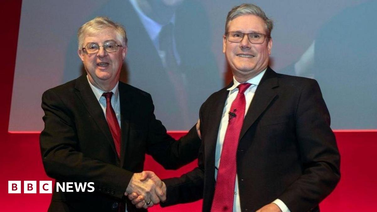 Mark Drakeford shaking hands with Sir Keir Starmer in front of a red background