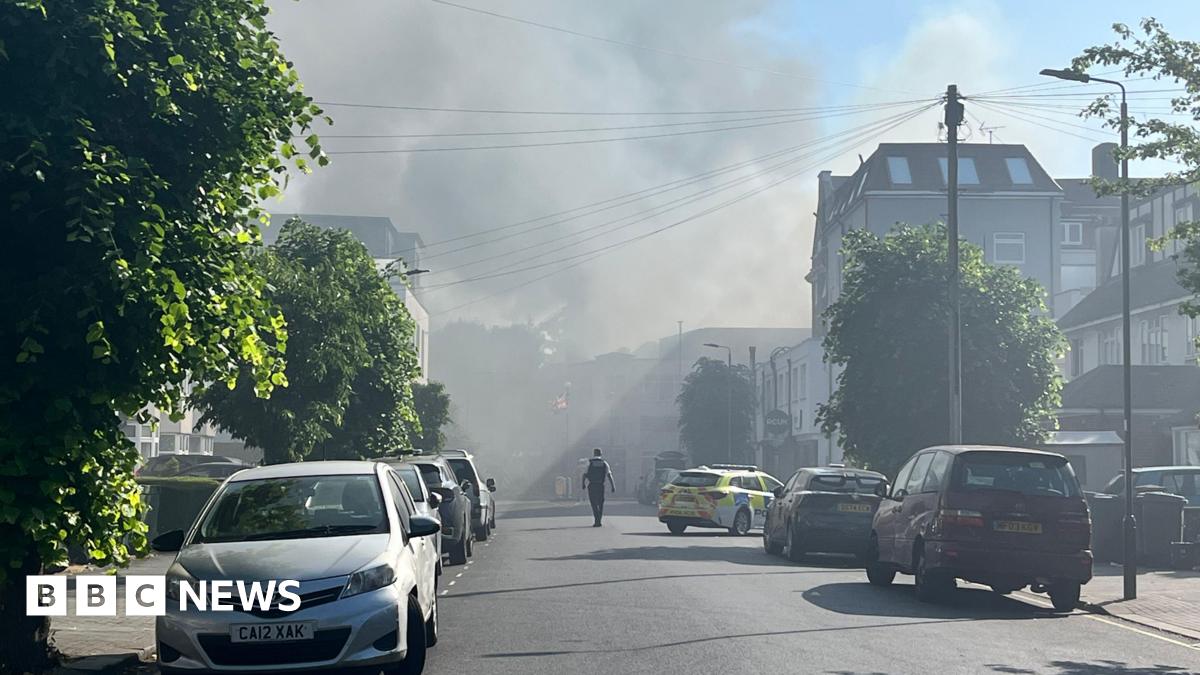 Police tape with smoky skyline beyond residential street with parked cars