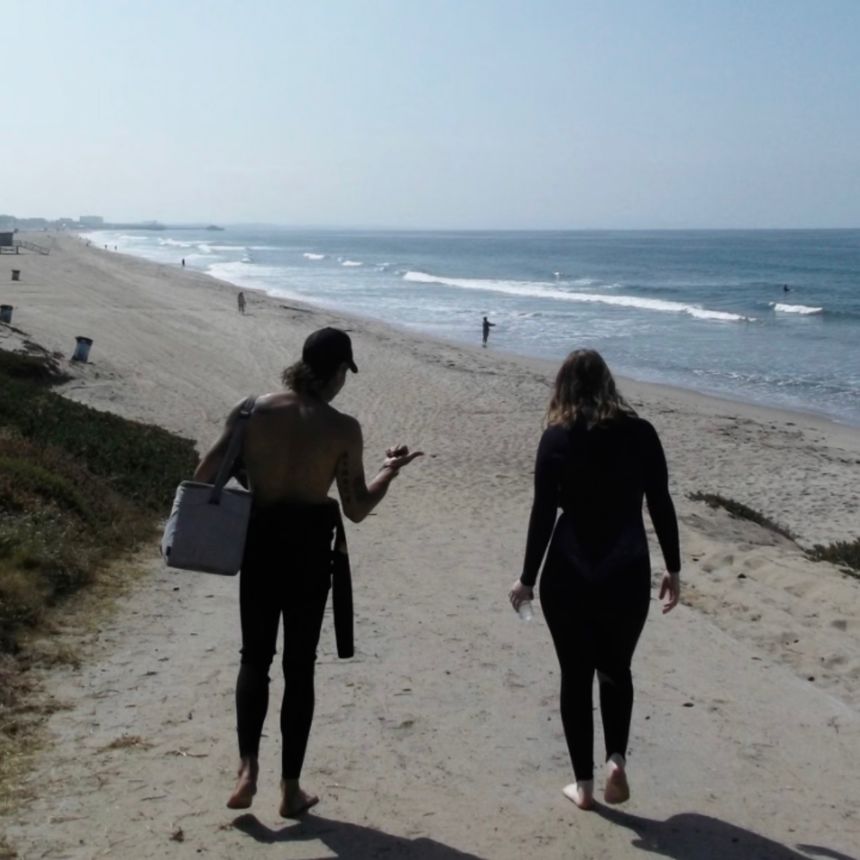 Adam Duford leads a customer to the waves in Santa Monica, California, as part of his new business, Santa Monica Surf Tours.