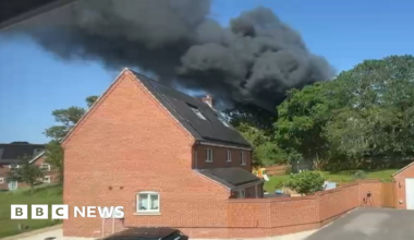 Dark smoke seen rising over a large red brick home.