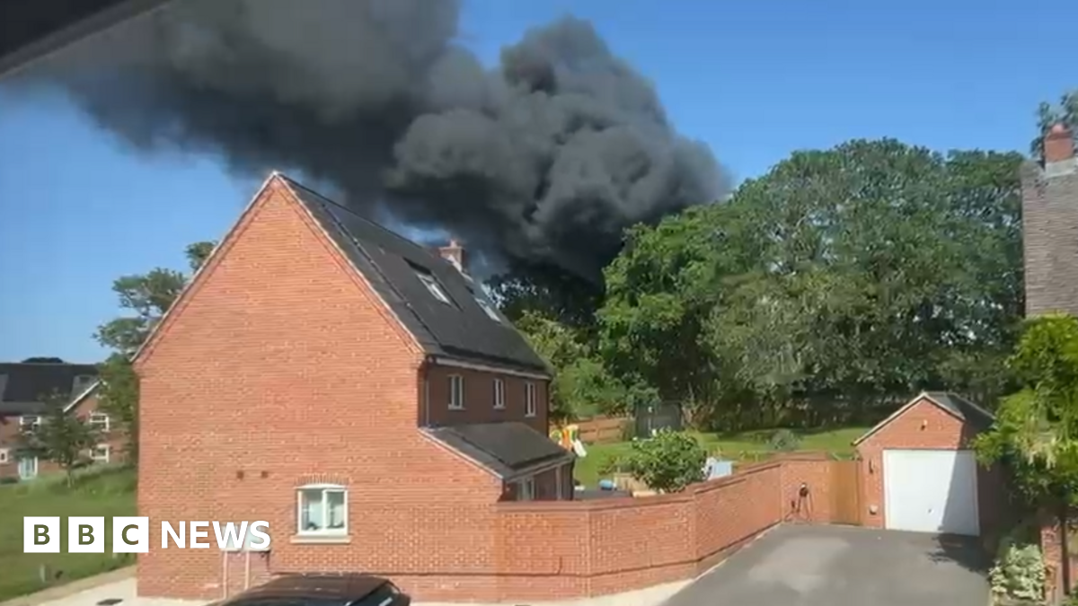 Dark smoke seen rising over a large red brick home.