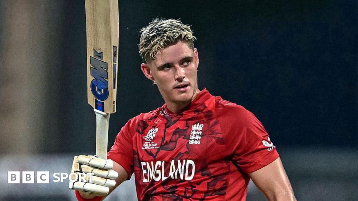 Jacob Bethell, in red team shirt, raises his bat after scoring a century for England