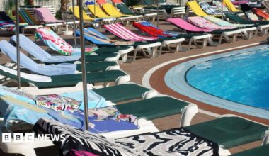 Towels on sunbeds around a swimming pool.