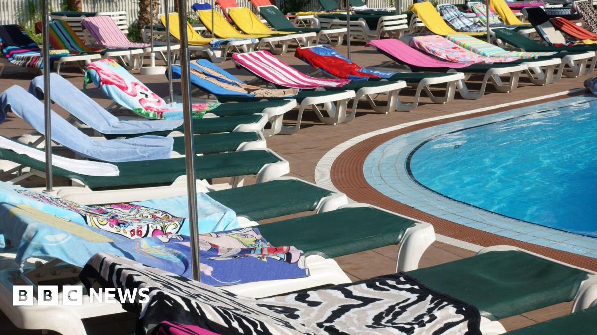 Towels on sunbeds around a swimming pool.