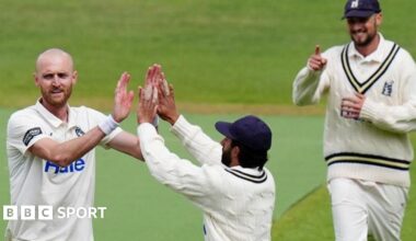 Olly Hannon-Dalby is given a double 'high five' by a team-mate after taking a wicket for Warwickshire