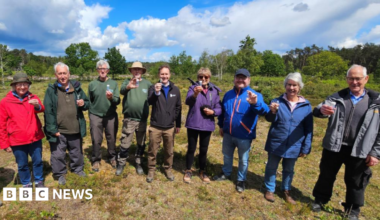 Nine conservation officers stood in a line outside holding test tubes
