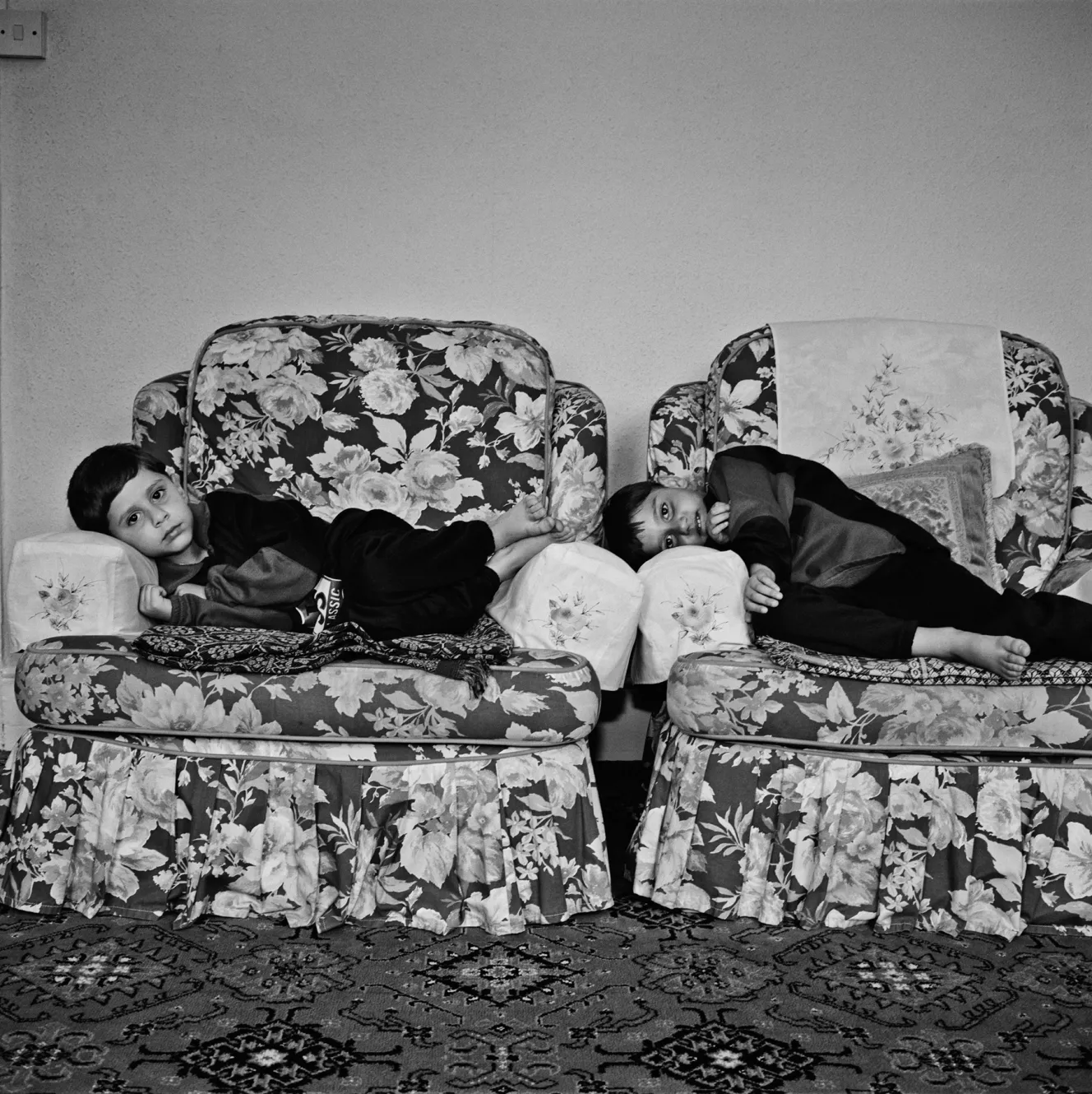 Two children, Luv and Kush, lie on floral chairs.