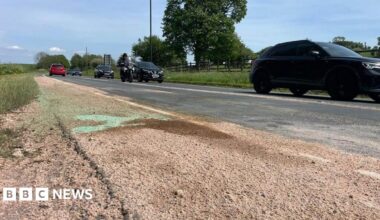 The road where the crash happened in Gisburn. A county road with cars and a motorbike heading to the right and a patch of sand in the foreground and to the left