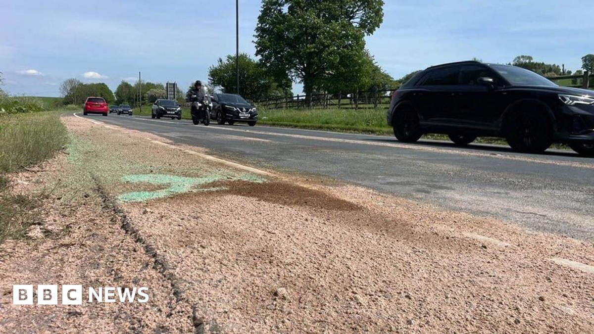The road where the crash happened in Gisburn. A county road with cars and a motorbike heading to the right and a patch of sand in the foreground and to the left