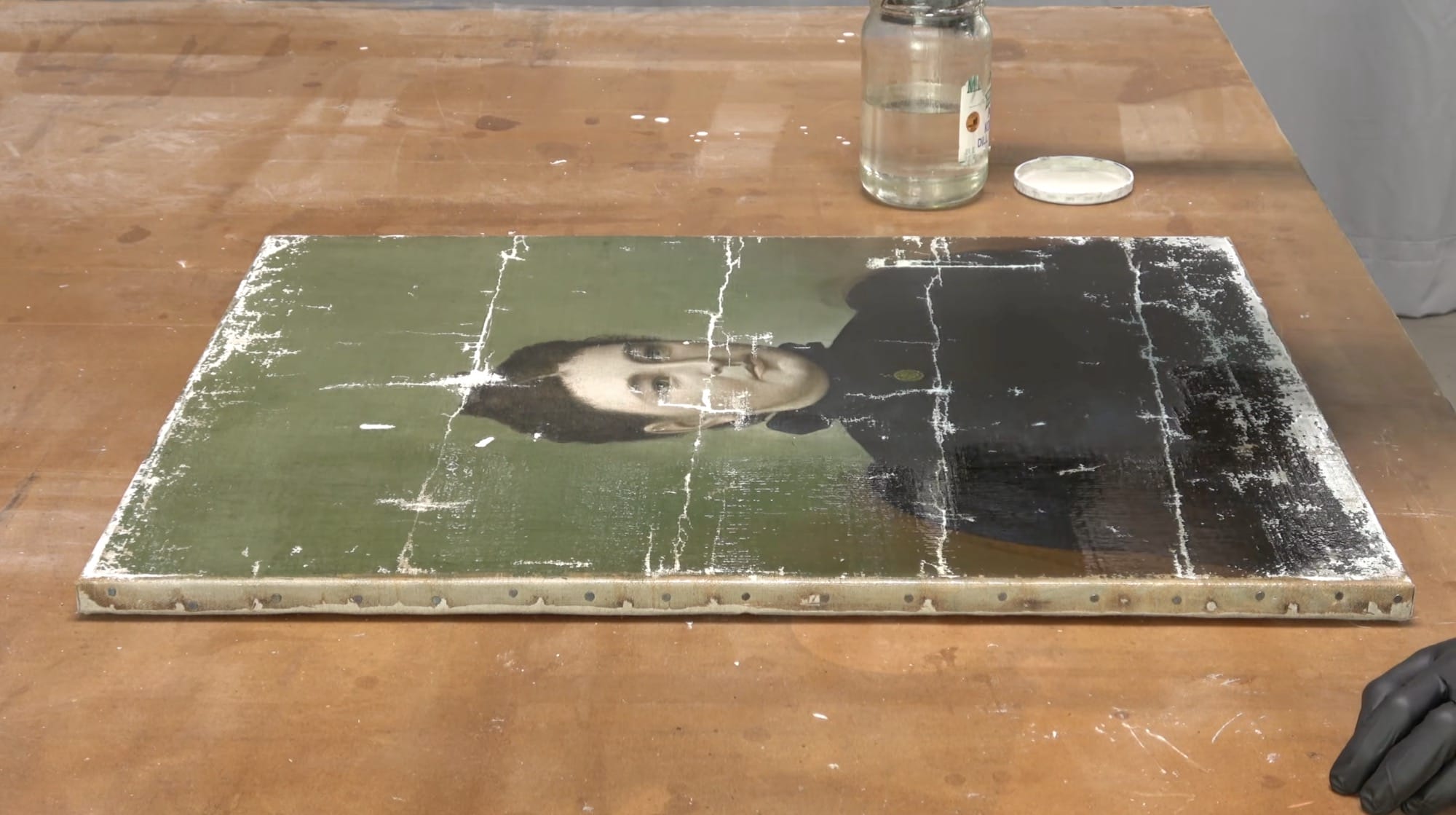 a still from a video by Baumgartner Restoration of a damaged portrait painting newly installed on a sturdy backing and stretcher bars