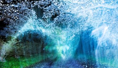 A dreamlike night landscape featuring a gravel path leading toward blooming cherry blossoms, obscured by ethereal blue and green light flares and motion blur.