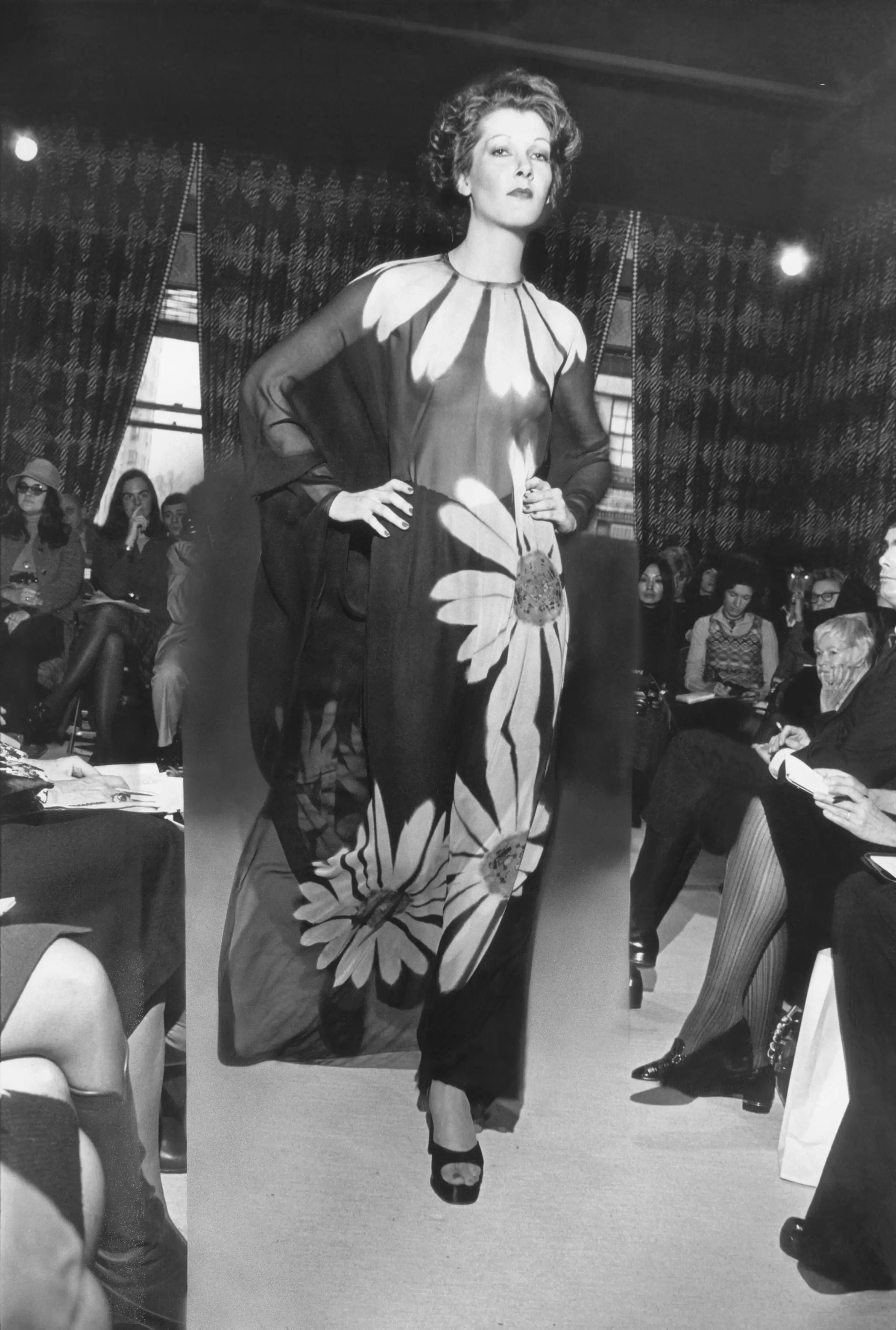 Model on the runway, wearing Halston's long, daisy-print caftan with chiffon trousers underneath.