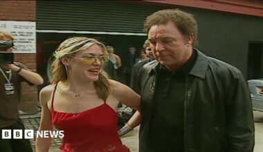 Cerys Matthews in a red dress and sunglasses with Tom Jones in a leather jacket. they arrived at the reopening of the Pop Factory in 2000.