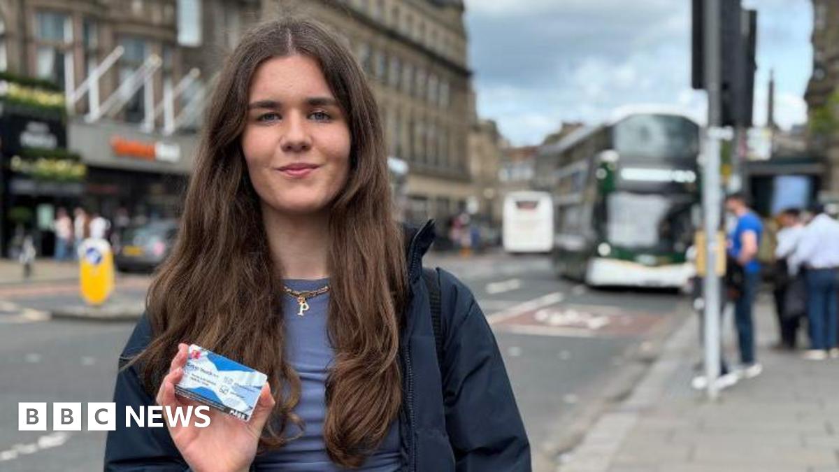 Poppy Fairbairn holds the National Entitlement Card towards the camera with a blurred Lothian Bus in the background.