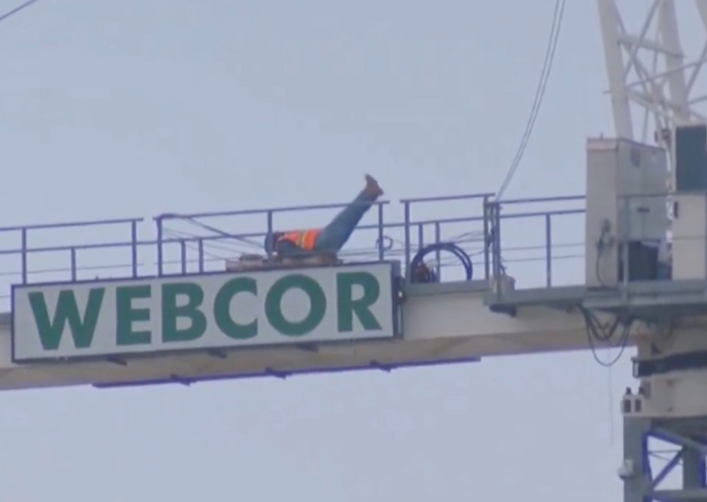 A construction worker exercising on top of a Webcor sign at a Cal Baptist vs. UCSB game.