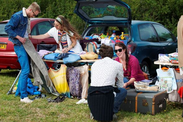 Sellers at a car boot sale on a sunny day