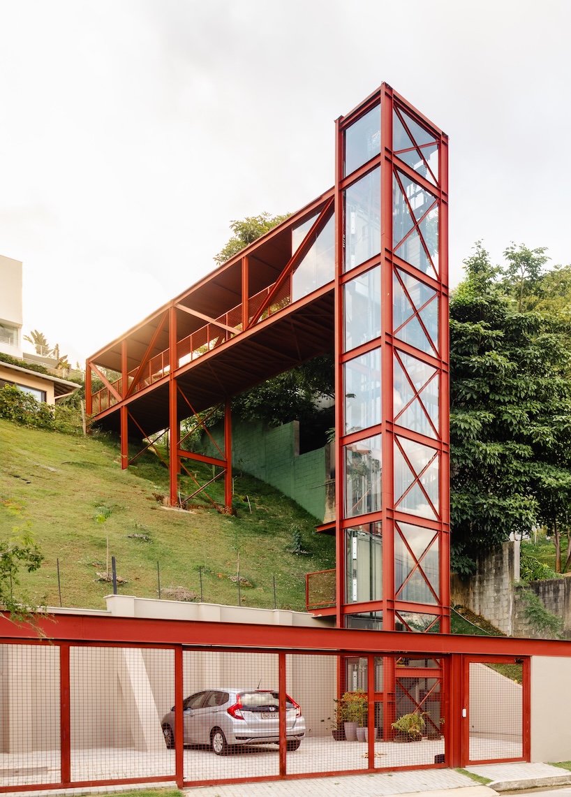 red elevated metal walkway extends casa castela across steep brazilian slope - 2