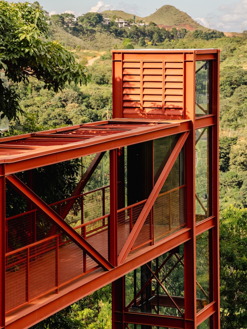 red elevated metal walkway extends casa castela across steep brazilian slope - 3