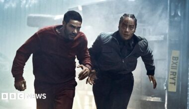 In a scene from the thriller series Prisoner, a prison transport officer and a prisoner run down a tunnel. They are handcuffed to each other and behind them is an overturned van that they were being transported in.