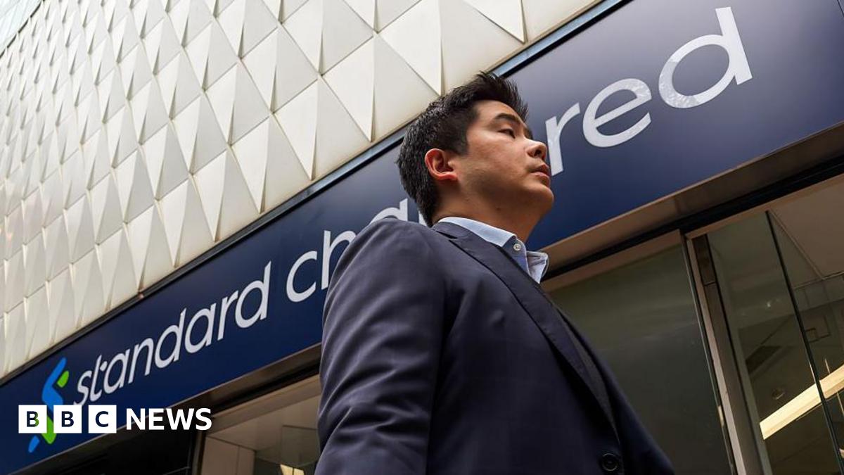 A pedestrian walks past a Standard Chartered bank branch on 17 March, 2026 in Hong Kong.