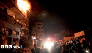 People look on as a fire burns in a building in central Gaza City.