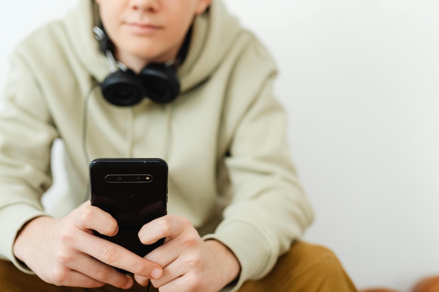 Boy wearing a hoodie looks at his phone. 