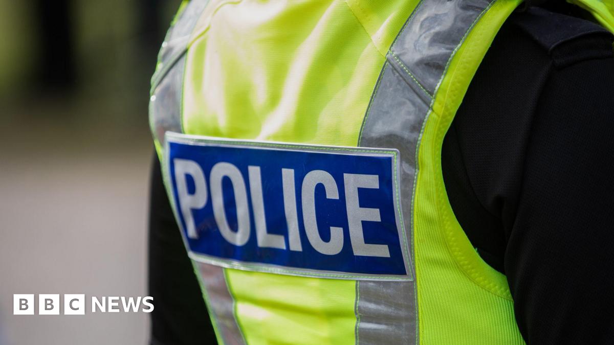 Close up of the back of a police officer, wearing a black t shirt and a high vis police vest