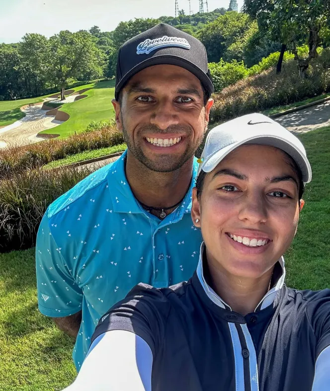 Aaron Rai and his wife Gaurika Bishnoi smiling on a golf course.