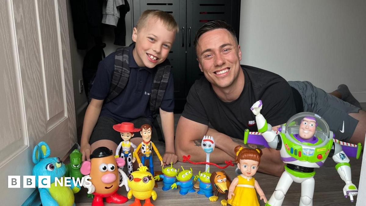 A child and his father lying at a doorstep with an array of toys from the Toy Story film franchise