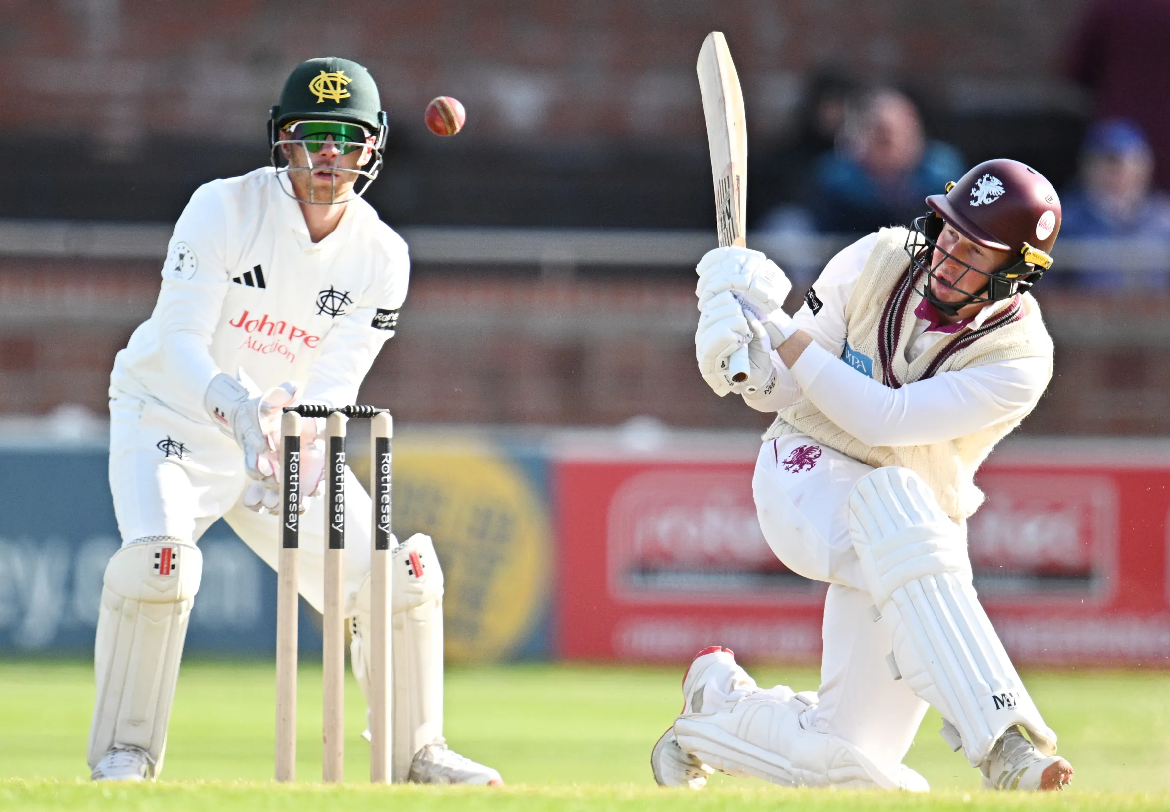James Rew of Somerset playing a shot as Kyle Verreynne of Nottinghamshire keeps wickets during a cricket match.