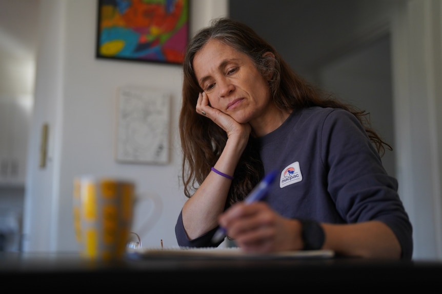 A woman sitting on a table writing.