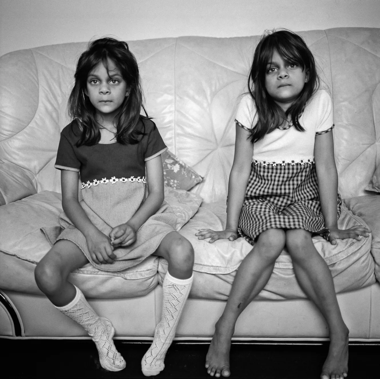 Two young girls, Riddhi and Siddhi, sit on a sofa.