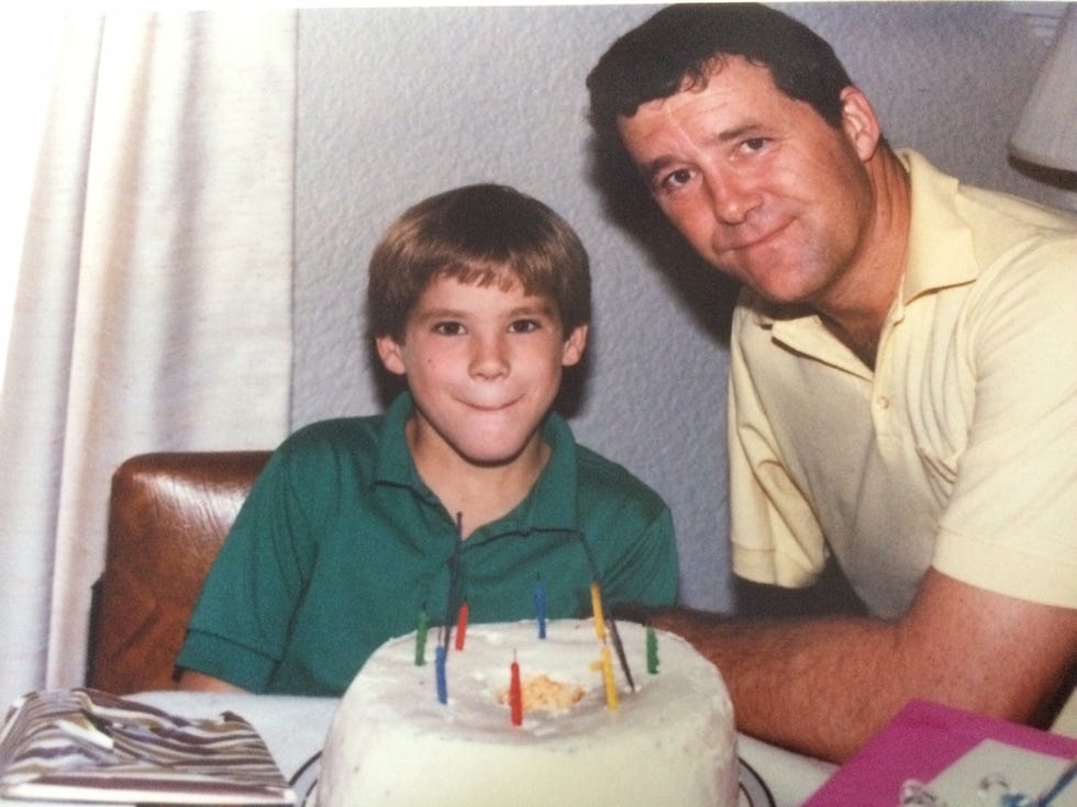 Child and adult celebrating a birthday with a cake