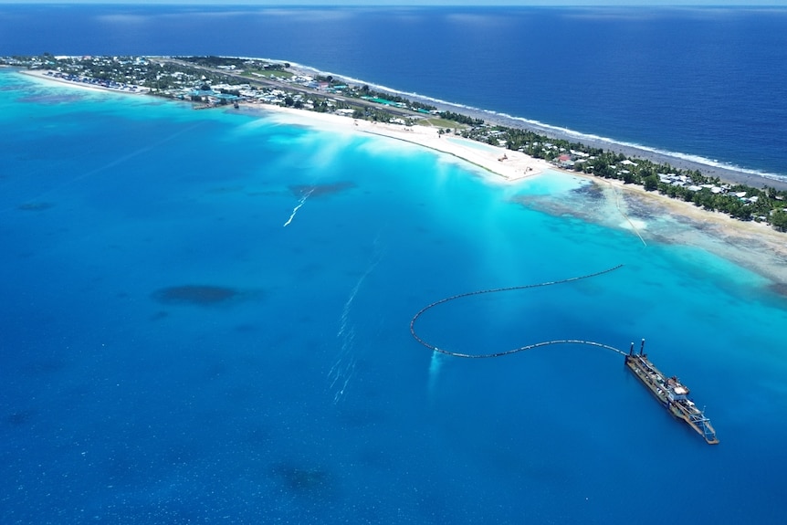This aerial shot of a land reclamation project shows a suction dredge at sea, with excavators and the airport in the distance.