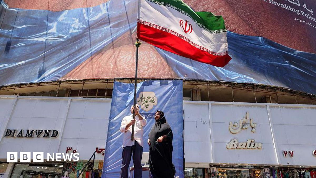 People hold up an Iranian flag in Tehran