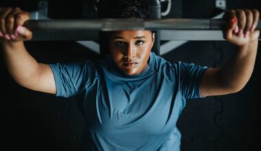 Directly above view of young woman on bench press exercising with barbell at gym