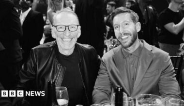 A black and white photo of DJ Calvin Harris in a suit with a T-shirt underneath alongside Mike Pickering in a leather jacket with dark glasses and grey receding hair